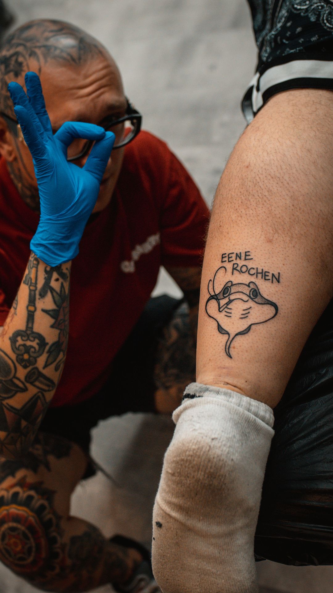 Tatuaż na łydce - tatuażyst klękający obok - Black Skulls Crew